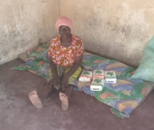 A lady receiving food support, sitting on her bed
